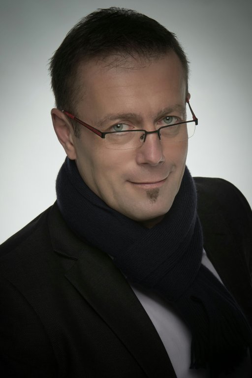 Szemüveges férfi sötétkék sálban, stúdióportré
